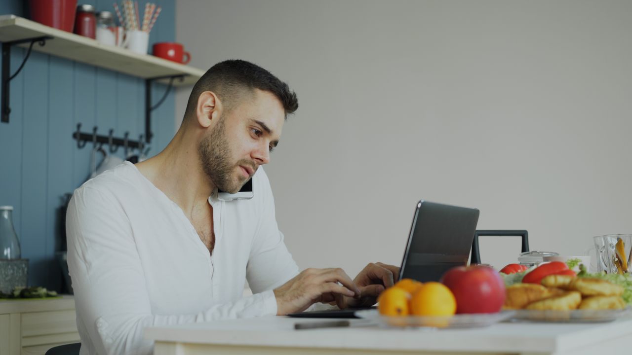 man-working-remotely-in-kitchen-with-laptop-36763311-ZwlIuaTKTXTffERvO5uL